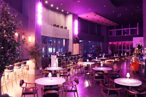 a restaurant with tables and chairs and purple lights at Avani Central Busan in Busan