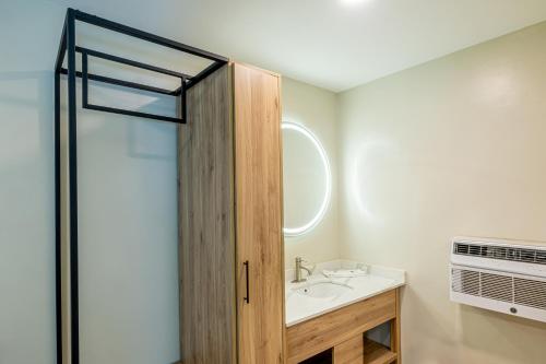 Exclusivo Inn and Suites Near Arlington Stadium في غراند براري: حمام مع حوض وباب دش زجاجي