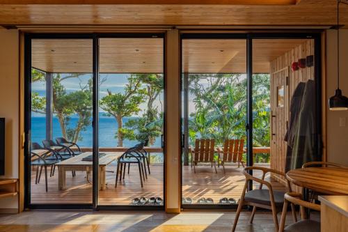 a dining room with glass doors and a table and chairs at ガーデンヴィラ白浜　KOTI in Shimoda