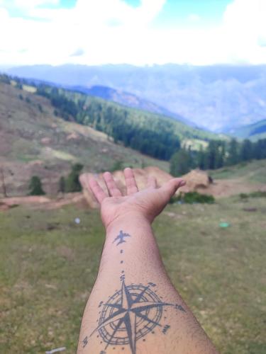 a hand with a tattoo of a cross and a compass at shake villa in Yeraoda