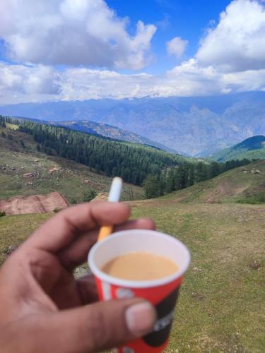 a person holding a cup of coffee on a hill at shake villa in Yeraoda