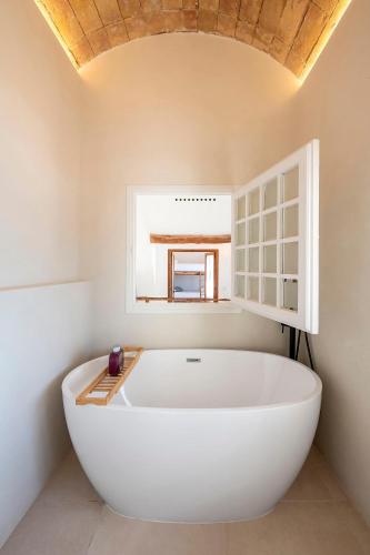 a large white bath tub in a bathroom with a window at Casa Concha Apartamentos in Calella de Palafrugell