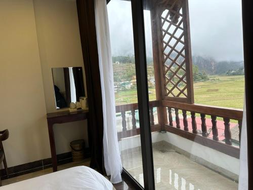 a bedroom with a window with a view of a field at Dongvan Ville Du H'Mong Hotel in Dồng Văn