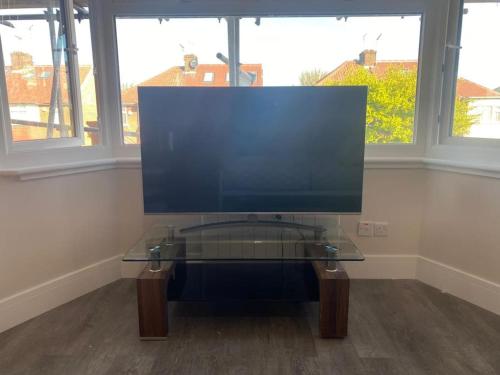 a computer monitor on a glass table in a room with windows at NEW! Brand New Beautiful Modern Apartment in London