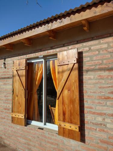 una ventana con puertas de madera en un edificio de ladrillo en Cabañas La Peperina in 