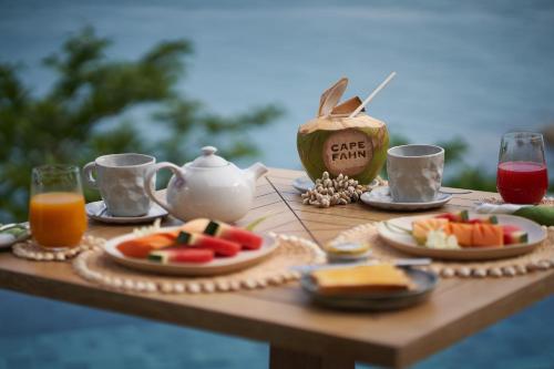 a wooden table with food and drinks on it at Cape Fahn Hotel Samui in Choeng Mon Beach