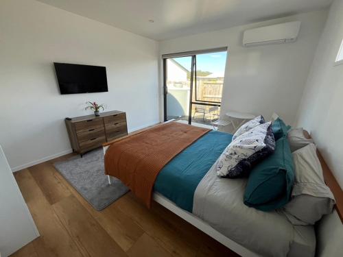 a bedroom with a large bed and a television at Ohana in Whitianga