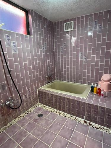 a bathroom with a tub and a tiled floor at ロビンホテルRobin Hotel in Yachimata