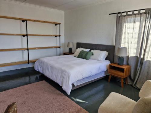 um quarto com uma grande cama branca e uma cadeira em 16 Mile View em Yzerfontein