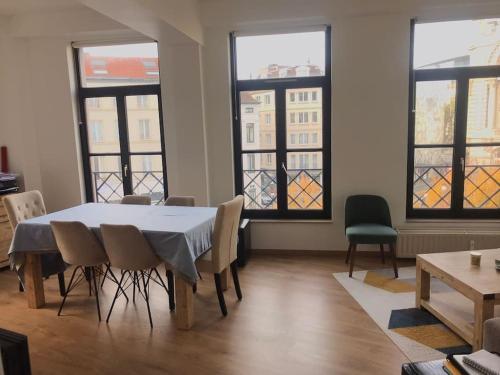 a dining room with a table and chairs and windows at Appartement proche grand place in Brussels