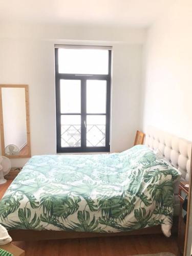 una camera da letto con un letto con un piumone verde e una finestra di Appartement proche grand place a Bruxelles