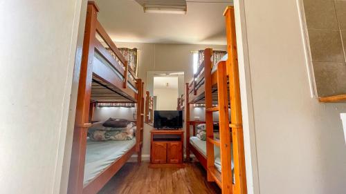 a room with four bunk beds and a tv at Capricorn Holiday Park in Carnarvon