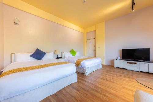 two beds in a hotel room with a flat screen tv at 光腳丫宜蘭民宿 in Dongshan