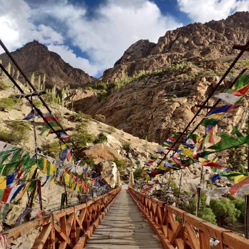 un puente con banderas de oración en las montañas en ARYA NATURE CAMP, en Dah