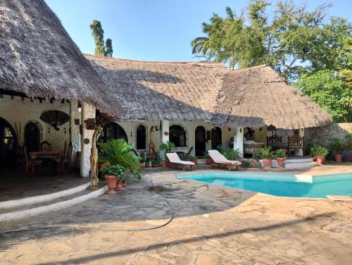 una casa con il tetto di paglia e una piscina di Villa Rosa a Mombasa