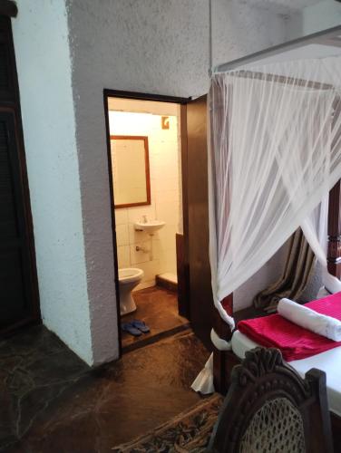 un bagno con un water e un letto in una stanza di Villa Rosa a Mombasa