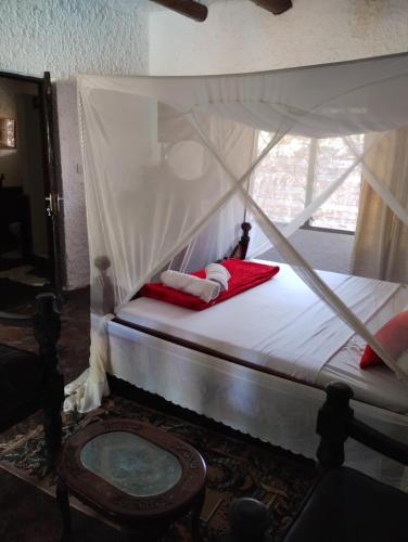 una camera da letto con un letto a baldacchino con una sedia e un tavolo di Villa Rosa a Mombasa