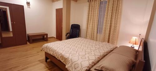 Aroma Inn في شيلونغ: غرفة نوم فيها سرير وكرسي