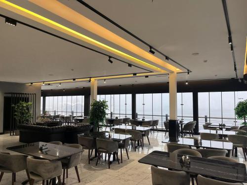um restaurante com mesas, cadeiras e janelas em Noor hotel em Baku