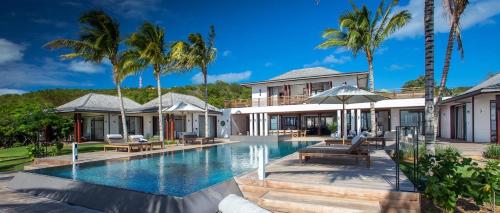 a swimming pool in front of a house with palm trees at Luxury Vacation Villa 3 in Gustavia