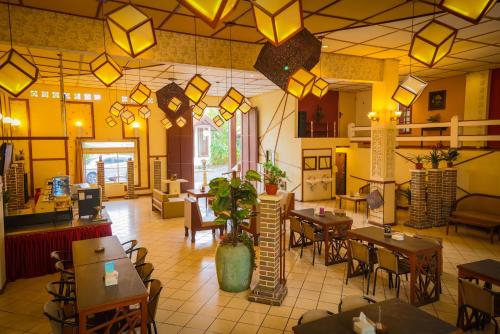 um restaurante com mesas, cadeiras e luzes em Family Hotel Gradia 2 em Batu