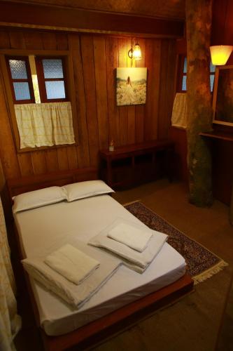 a bed in a wooden room with towels on it at Cure Monastery Family Resort in Marayoor
