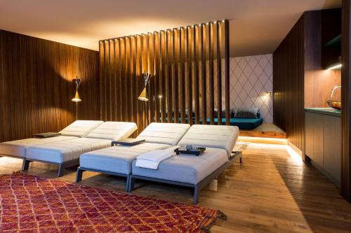 a living room with three white beds and a rug at ANTON Dolomites Hideaway in Brunico