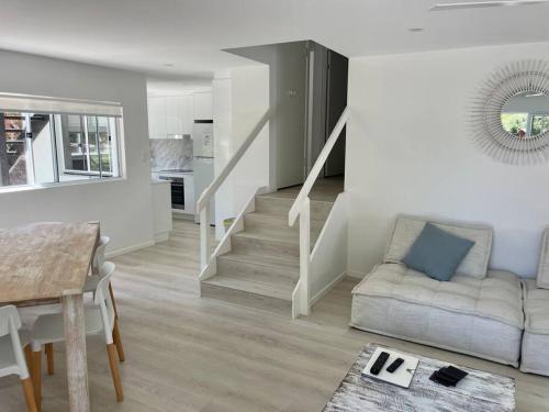 a living room with a staircase and a couch at Location Location, sunshine beach, 100 m to beach( HA3) in Sunshine Beach