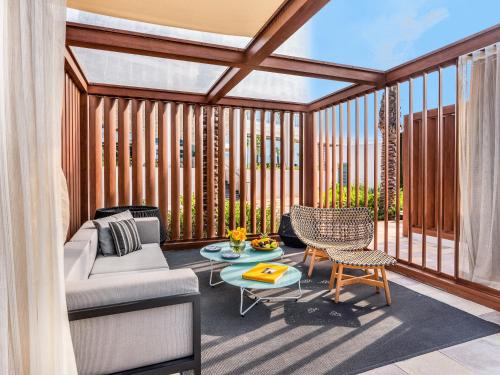 a screened in porch with a couch and a table at Rixos Gulf Hotel Doha in Doha