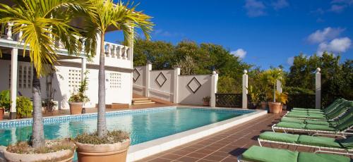 a swimming pool with chaise lounge chairs and palm trees at Ocean View Villa Full House Rate home in Cap Estate