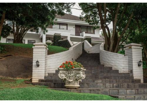 a staircase in front of a house with a vase with flowers at Sheppard Boutique Hotel in Nelspruit