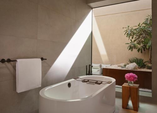 a white bath tub in a bathroom with a mirror at The Ritz-Carlton Ras Al Khaimah, Al Wadi Desert in Ras al Khaimah