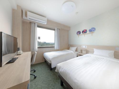 a hotel room with two beds and a flat screen tv at Tabino Hotel EXpress Narita in Narita