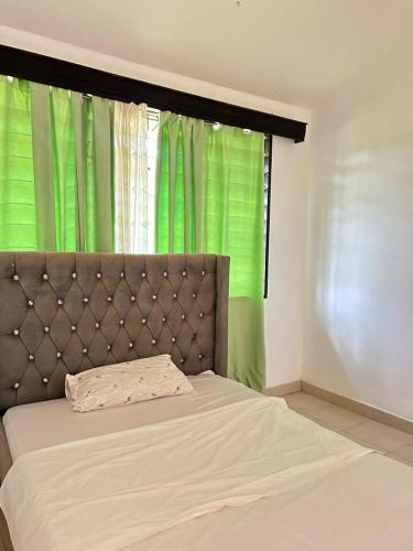 1 cama en un dormitorio con cortina verde en Mopearlz 4bedroom villa Nyali, en Mombasa