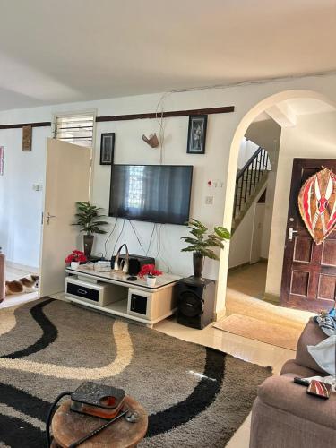 sala de estar con TV de pantalla plana y sofá en Mopearlz 4bedroom villa Nyali, en Mombasa