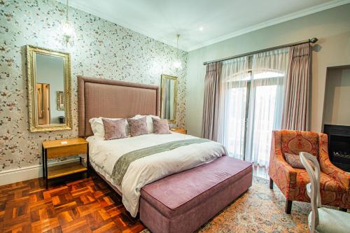a bedroom with a bed and a chair and a mirror at The Rasmus in Pretoria