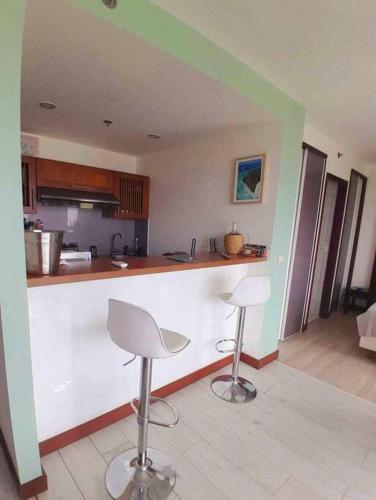 a kitchen with two stools and a counter top at Appartement avec piscine Anse Vata Nouméa in Noumea