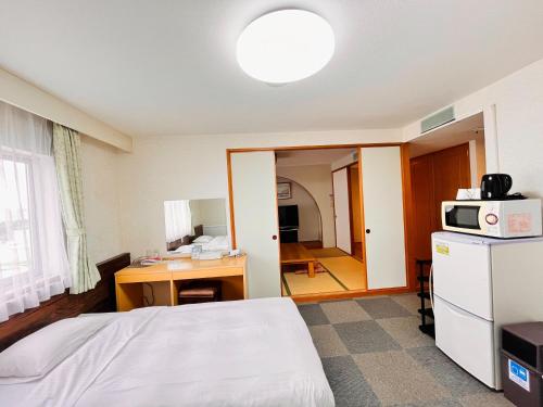 那覇市にあるホテルオロックス HotelOroxのベッド、デスク、電子レンジが備わる客室です。