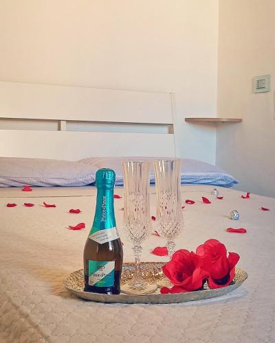 a bottle and two glasses and roses on a bed at Jeppson home in Terni