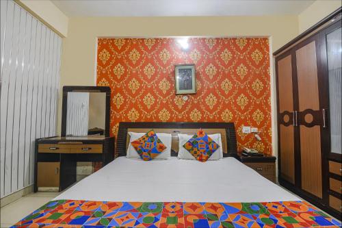 1 dormitorio con cama y pared roja en FabHotel Maadhavam Residence en Patna