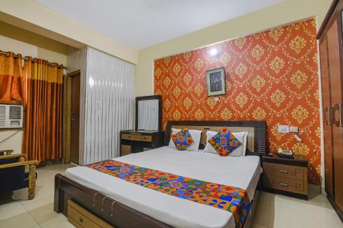 um quarto com uma cama e uma parede vermelha em FabHotel Maadhavam Residence em Patna