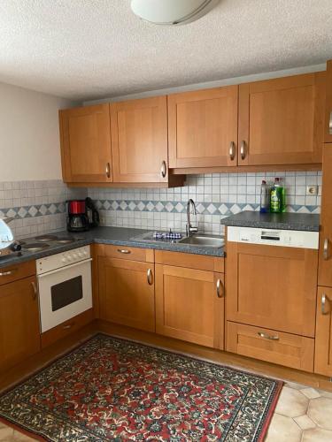 una cocina con armarios de madera y una alfombra en Gästehaus Huber en Holzgau