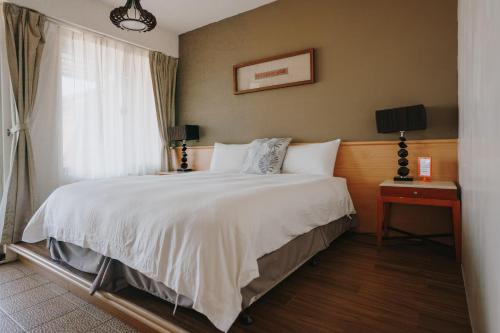 um quarto com uma cama grande e uma janela em Mountain Traveler Inn em Jiufen