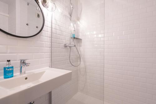 a white bathroom with a sink and a shower at PoMo Hôtel & Restaurant in Échirolles