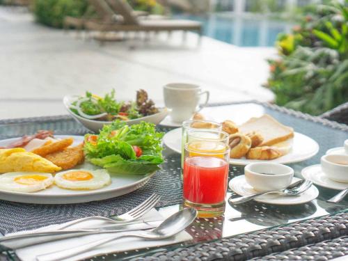 Mercure Pattaya Ocean Resort في باتايا سنترال: طاولة مع أطباق من البيض والخبز والمشروبات