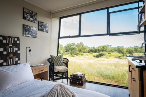 - une chambre avec un lit, une chaise et une fenêtre dans l'établissement Kamoka Camp, à Hoedspruit