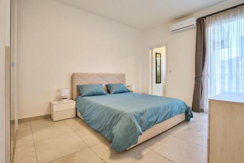 sypialnia z łóżkiem z niebieską pościelą i oknem w obiekcie 2 Bedroom Apartment St. Julians w mieście St. Julian’s