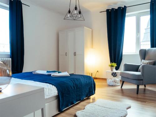 Schlafzimmer mit einem Bett mit blauer Bettwäsche und einem Stuhl in der Unterkunft Regina Elisabeta Apartment in Bukarest