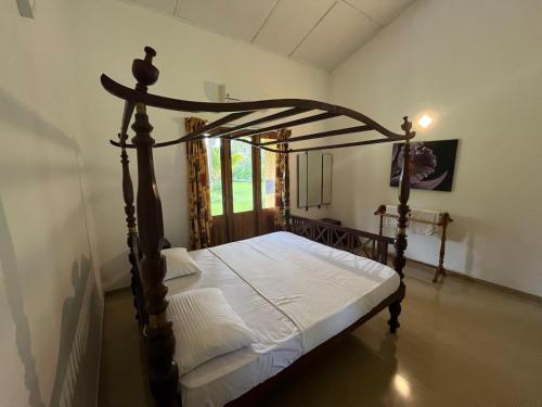 a bedroom with a canopy bed with white sheets at Rivendell Twisted Tree in Kurunegala