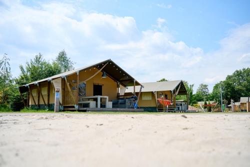 a small yellow house with a tent on the beach at Glamping Nieuw Heeten in Nieuw-Heeten